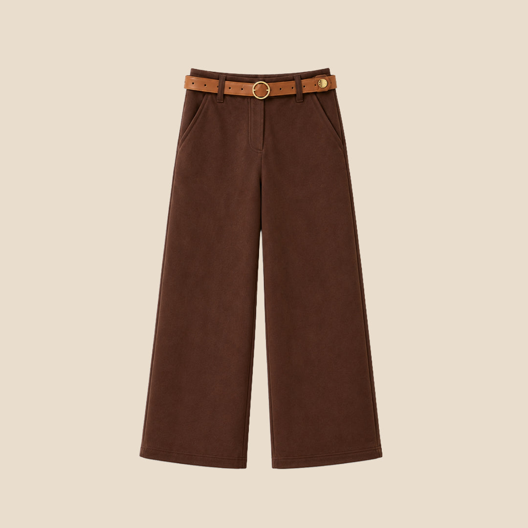 A model wearing a pair of wide-leg brown trousers with a brown belt, paired with a beige ribbed cardigan and beige slip-on shoes, set against a solid light beige background.