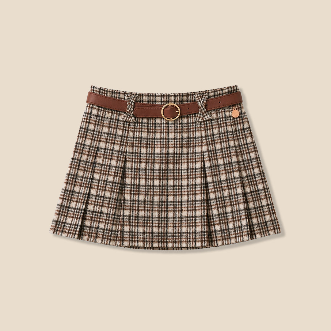 A model wearing a pleated plaid mini skirt in beige, brown, and black, paired with a white blouse and a brown belt with a gold ring, set against a solid beige background.