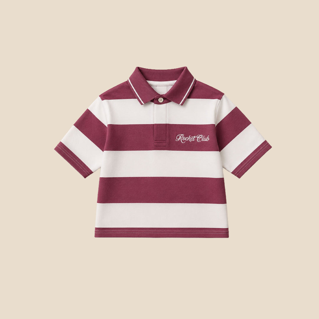A young boy wearing a short-sleeve polo shirt with horizontal burgundy and white stripes, featuring a small white script logo on the chest, paired with khaki cargo pants, set against a solid beige background.